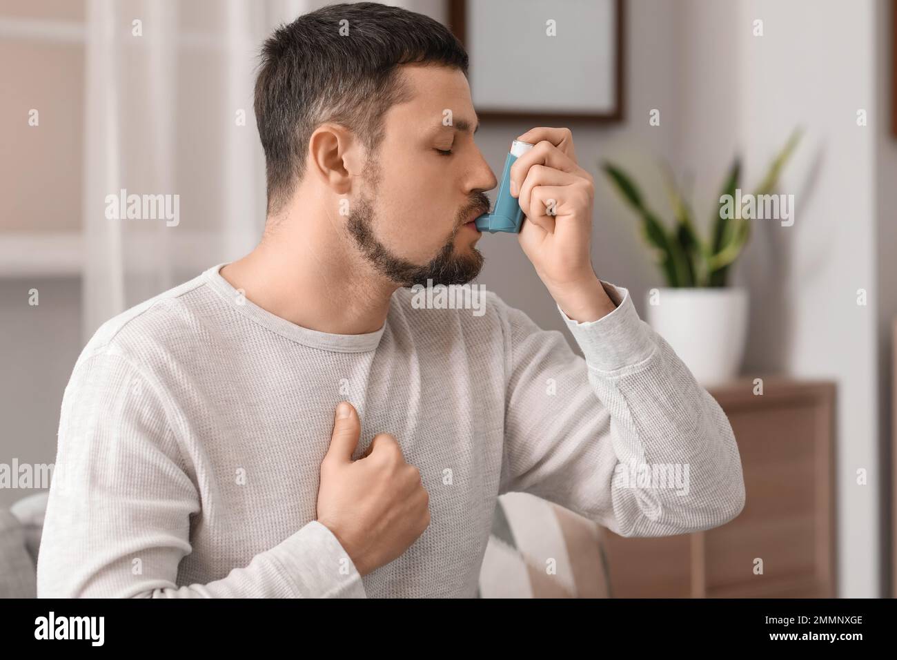 Sick man using inhaler at home Stock Photo - Alamy