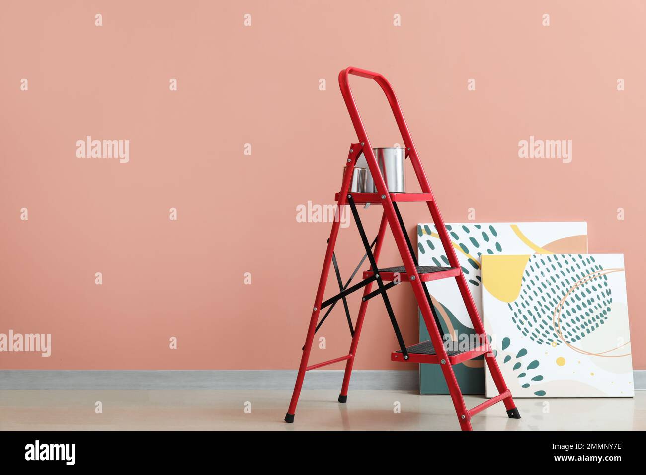 Maintenance ladder with cans of paint and paintings near color wall ...