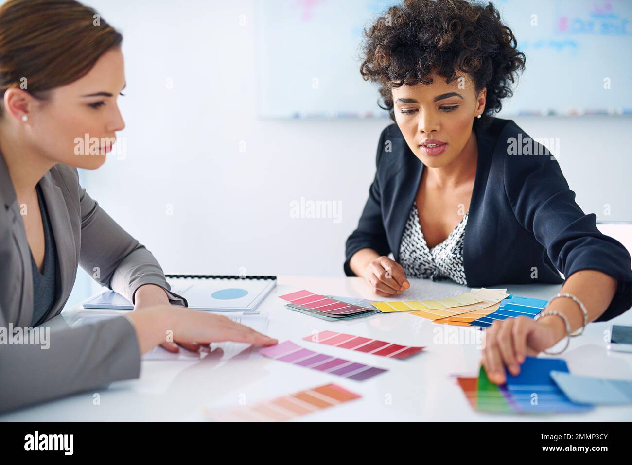 Creating a professional color scheme for their brand. two designers looking at color swatches. Stock Photo