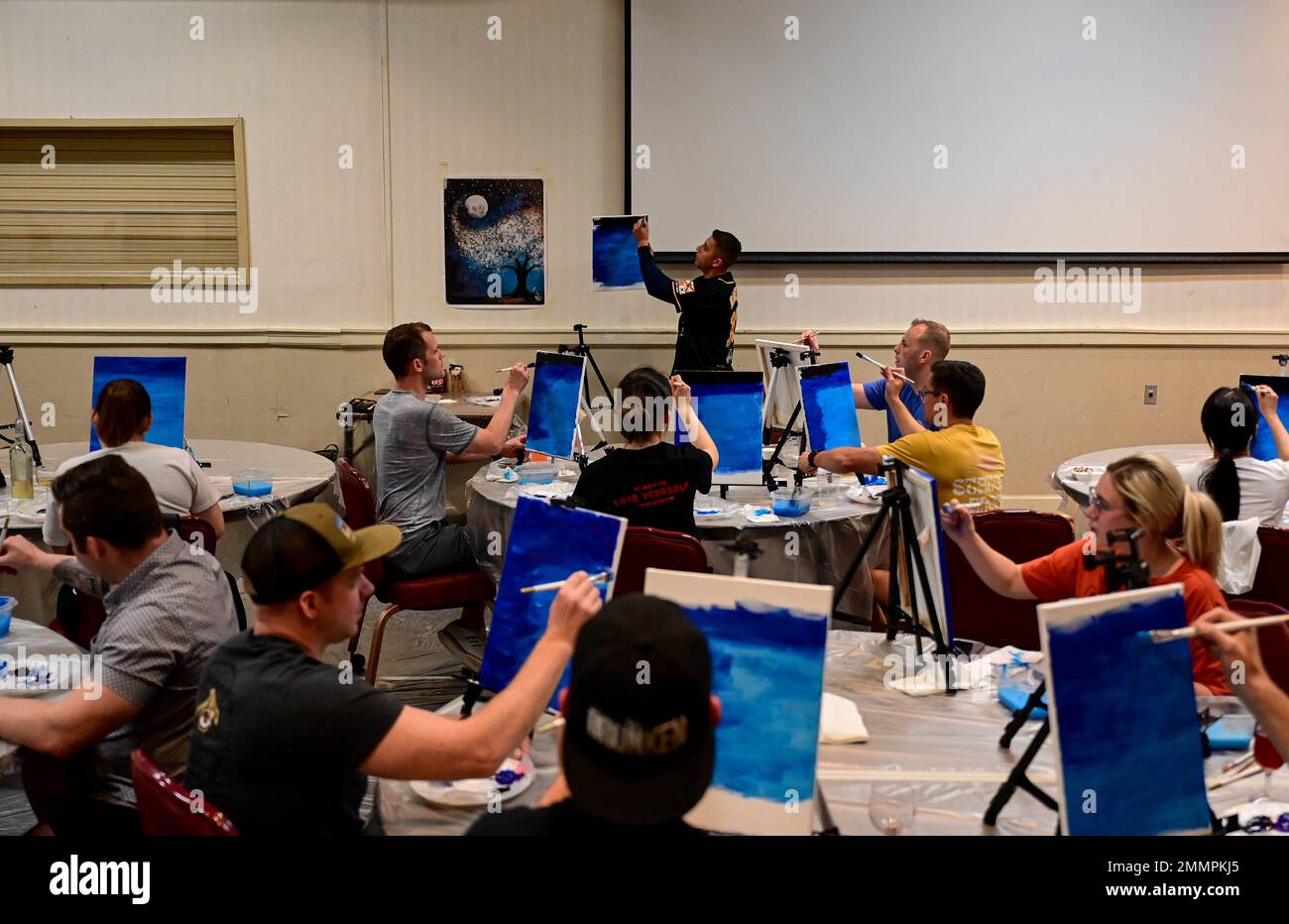 Attendees at a “Paint N’ Sip” class follow instructor guidance at