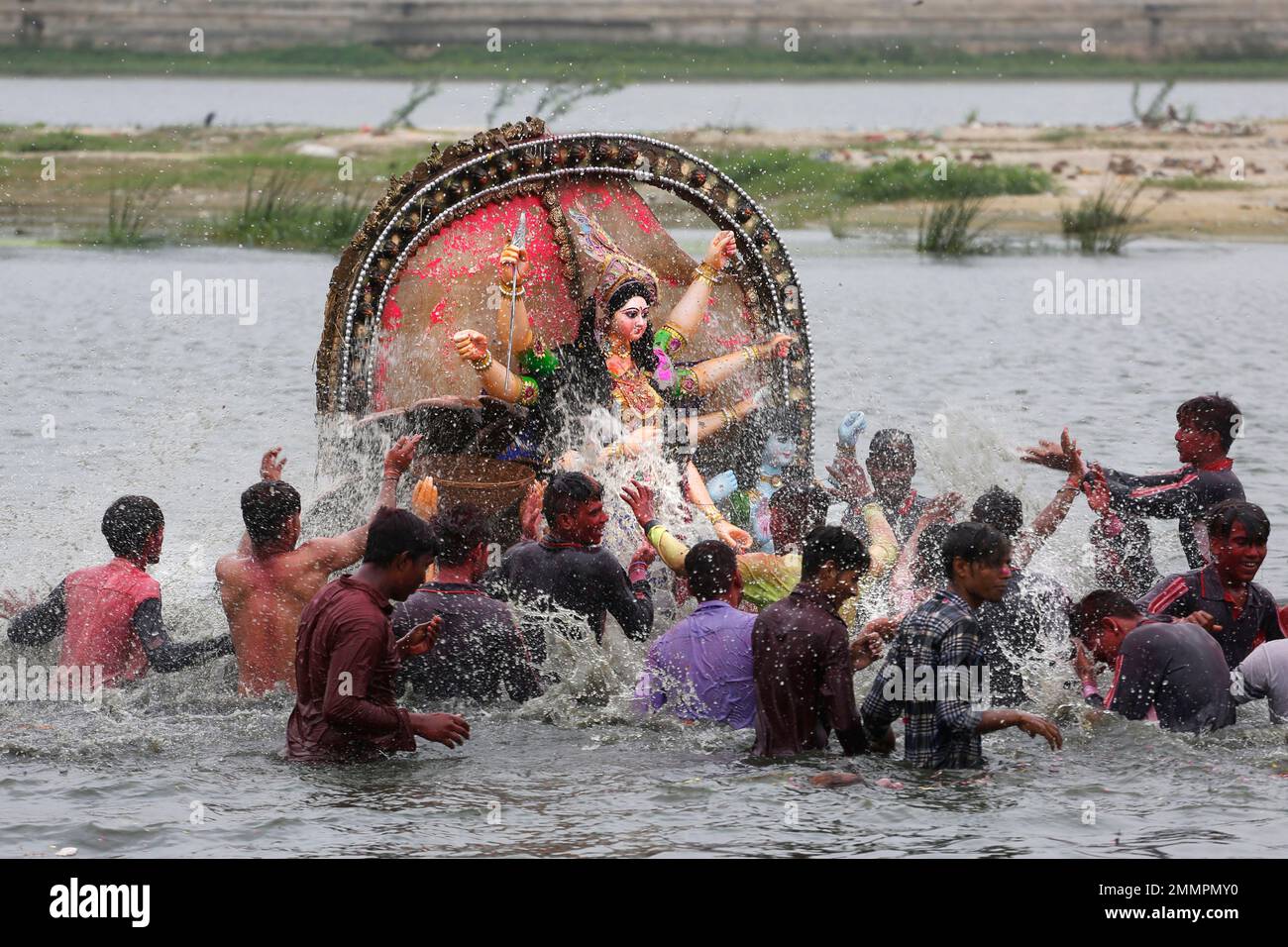 Indians immerse an idol of Hindu goddess Dashama on the bank of river ...