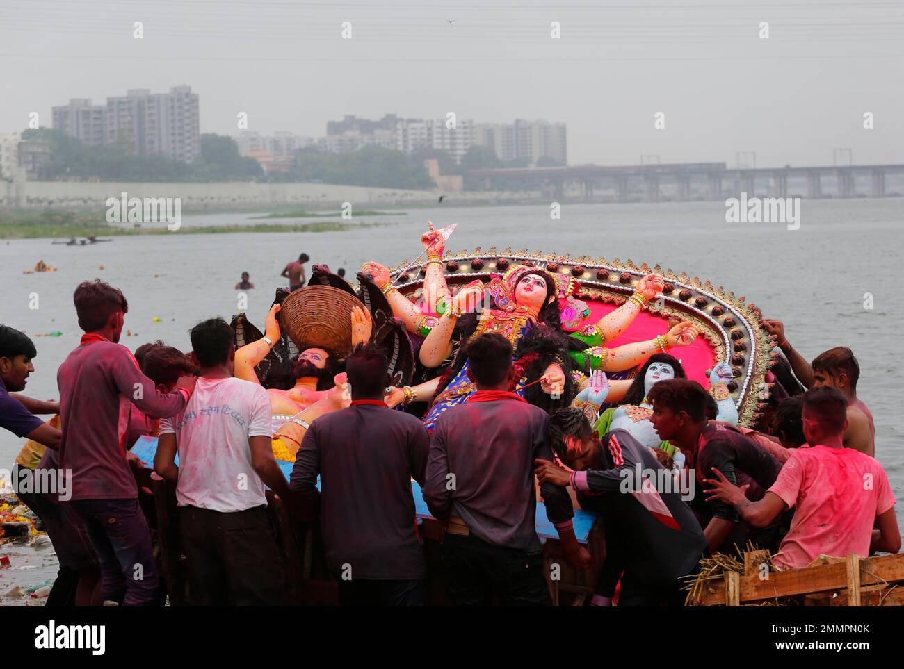 Devotees immerse an idol of Hindu goddess Dashama on the bank of the ...