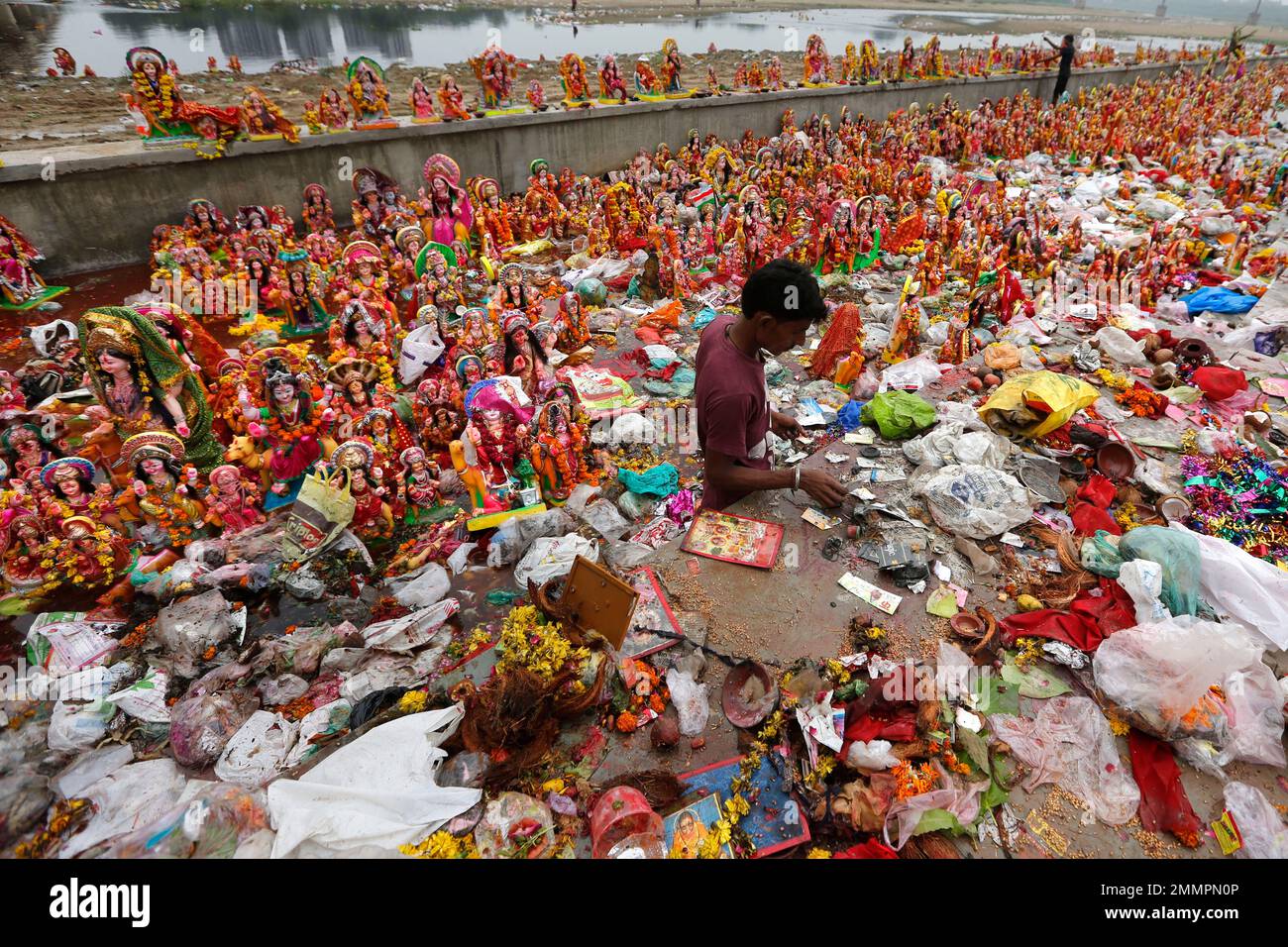 An Indian man looks for reusable items amid idols of Hindu Goddess ...