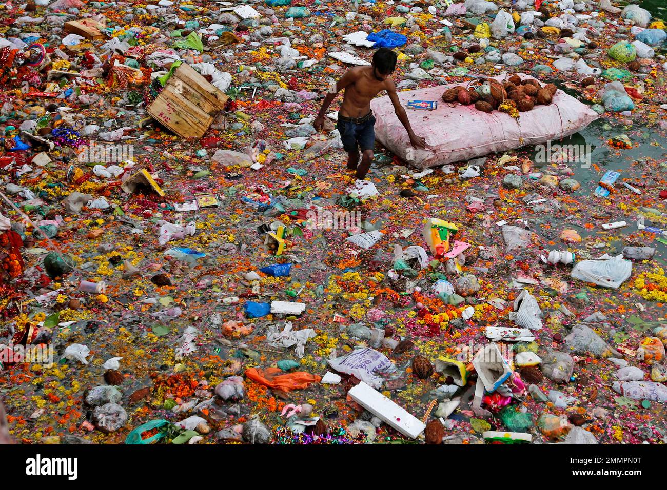An Indian man searches for reusable items amid offerings and worship