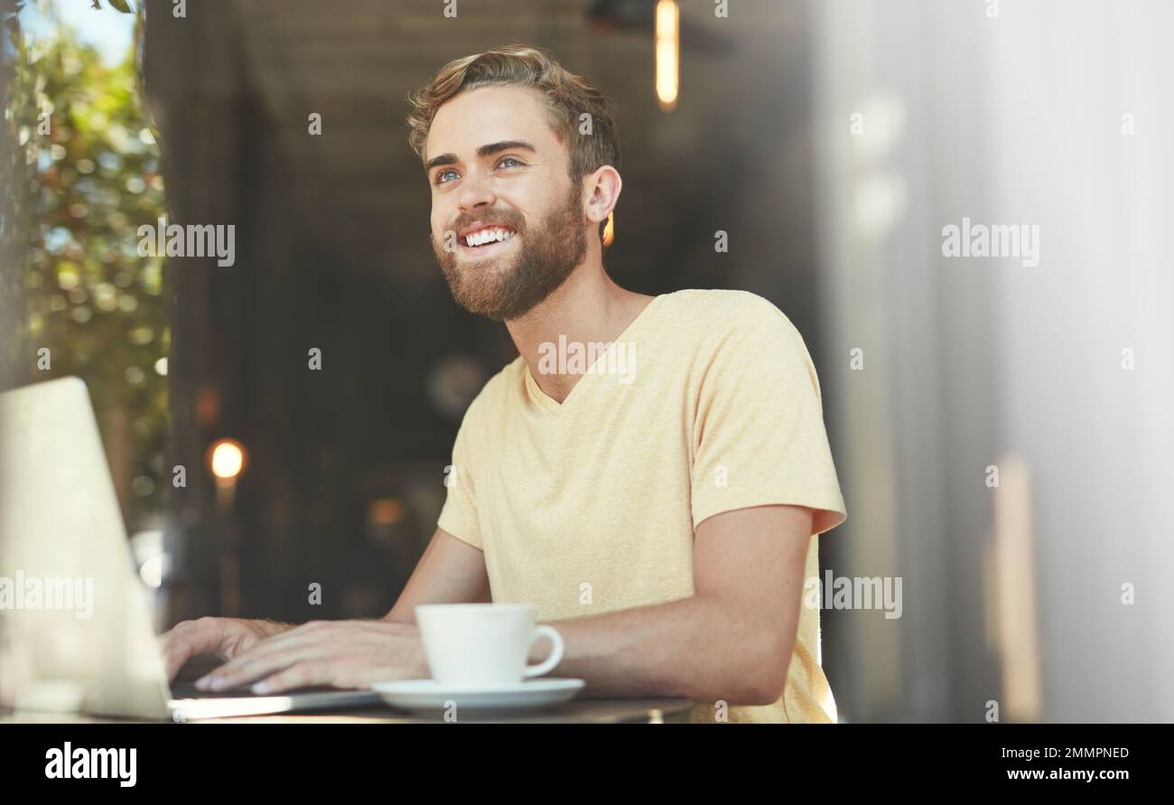 Catching up on some work at the cafe. a young man using a laptop in a cafe. Stock Photo