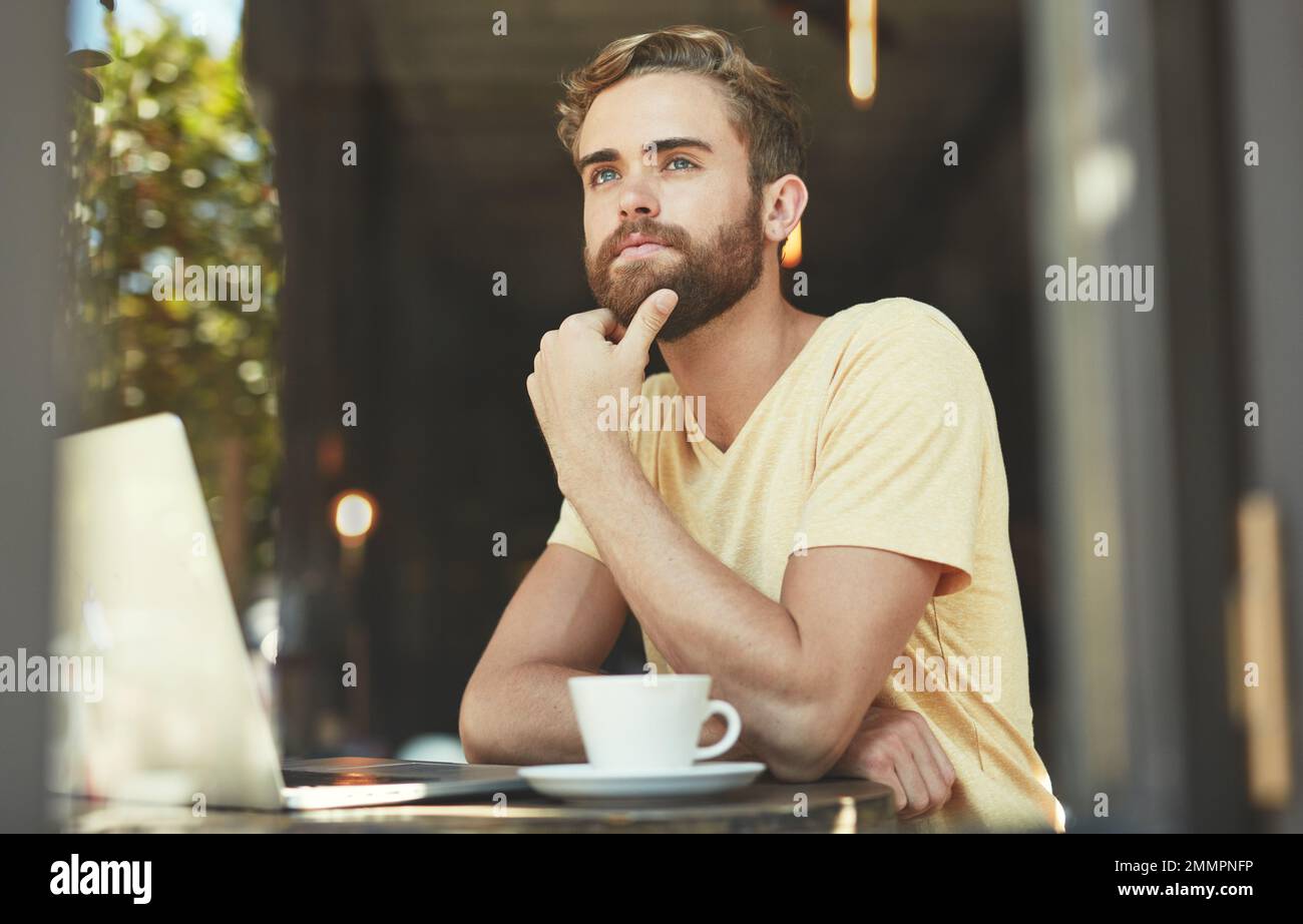 His quiet corner of the cafe. a young man using a laptop in a cafe. Stock Photo