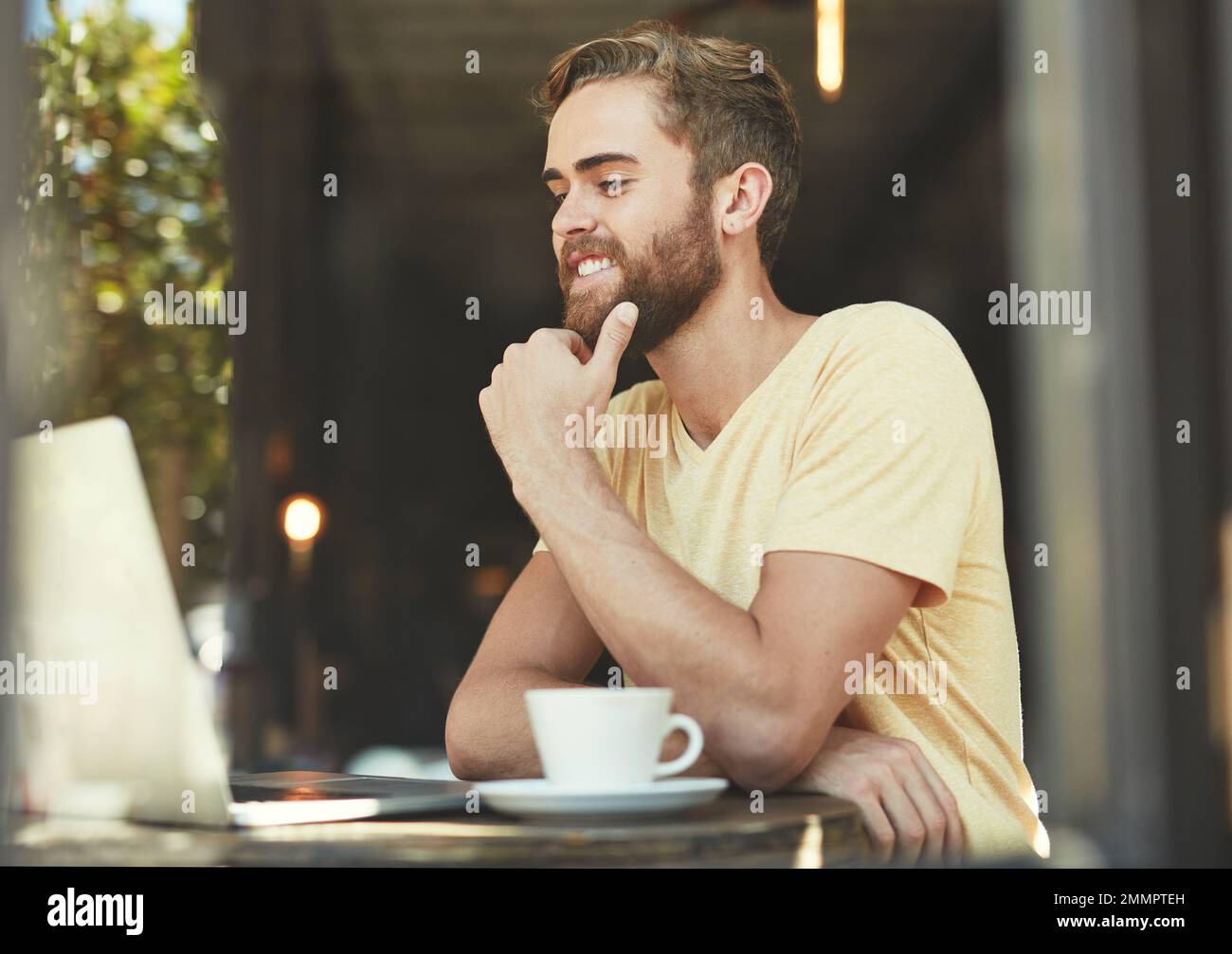 Giving the cafe a great write up on his blog. a young man using a laptop in a cafe. Stock Photo