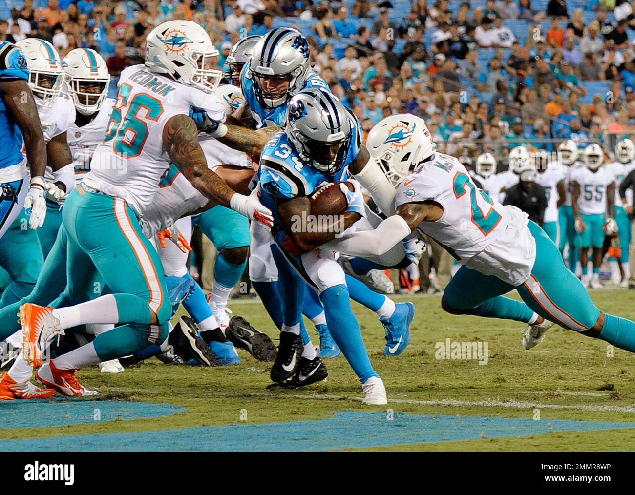 Carolina Panthers' Cameron Artis-Payne (34) runs through Miami Dolphins'  Quincy Redmon (66) and Torry McTyer (24) for a touchdown in the second half  of a preseason NFL football game in Charlotte, N.C., Friday, Aug. 17, 2018.  (AP Photo/Mike McCarn