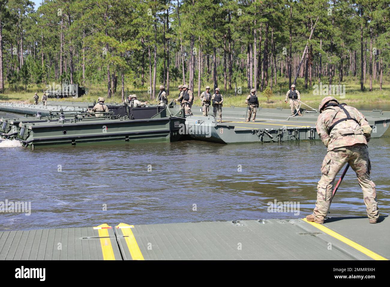 U.S. Army Soldiers assigned to the 497th Multi-Role Bridge Company, 92nd Engineer Battalion, use an M1120 Heavy Expanded Mobility Tactical Truck Load Handling System to retrieve each separate bay of a bridge after a Wet Gap Crossing exercise on Fort Stewart, Georgia Sept. 22, 2022. Each bay folds into itself after being lifted by a crane before being transported. Stock Photo