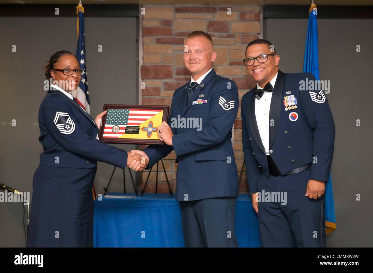 U.S. Air Force Staff Sgt. Jonathan Brown, center, accepts the Commandant's Award from U.S. Air Force Senior Master Sgt. Daisha Brown, 49th Logistics Readiness Squadron material maintenance superintendent, left, and Holloman Airman Leadership School Commandant U.S. Air Force Tech. Sgt. Briton Hurdle during an ALS graduation at Holloman Air Force Base, New Mexico, Sept. 22, 2022. The commandant leadership award is selected by the ALS commandant and is presented to the student who demonstrates the characteristics of an effective leader. Stock Photo