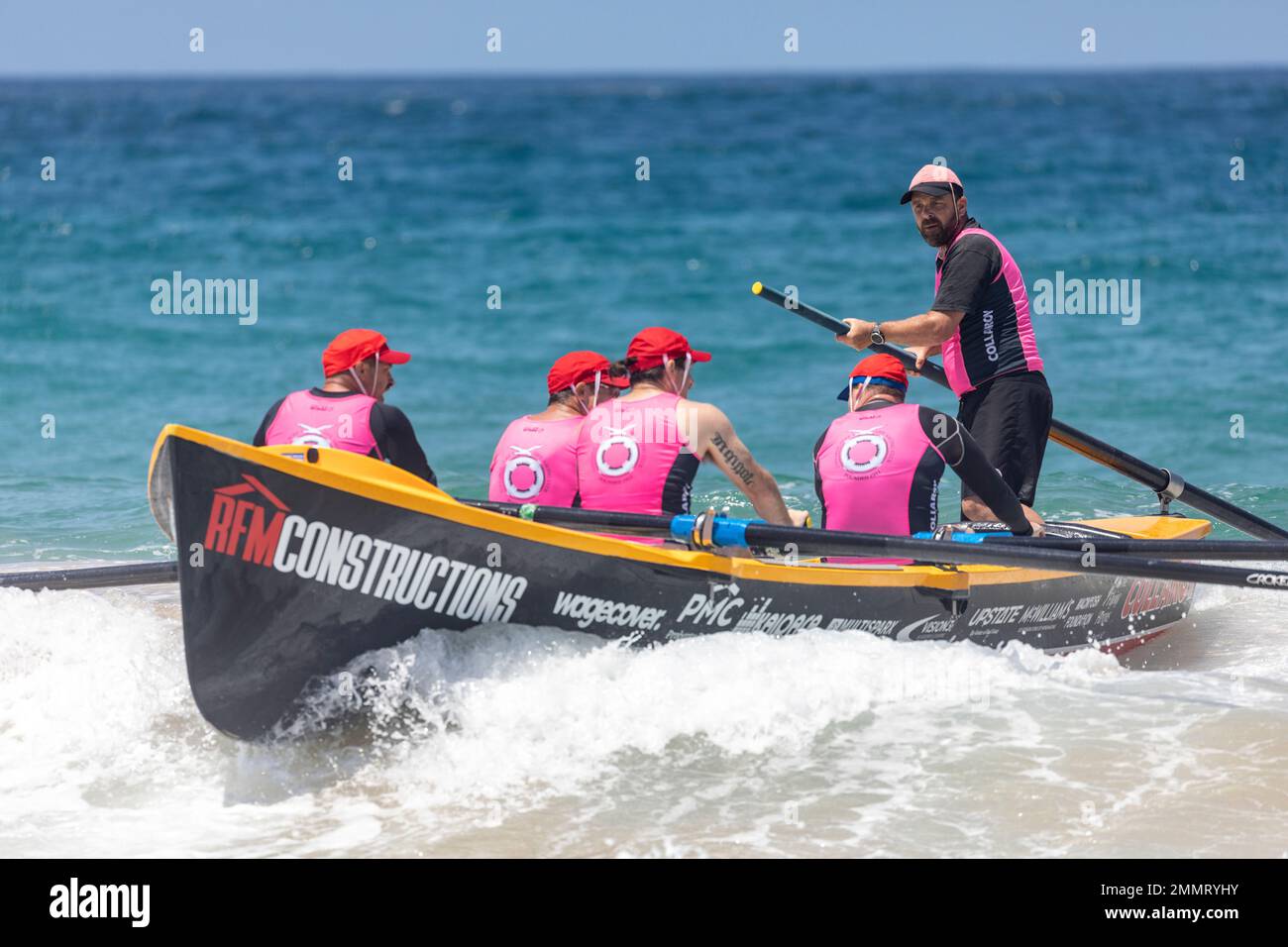 Sydney surfboat racing carnival at North Narrabeen beach, local surf club Collaroy mens team row surfboat towards shore, Sydney,NSW,Australia Stock Photo