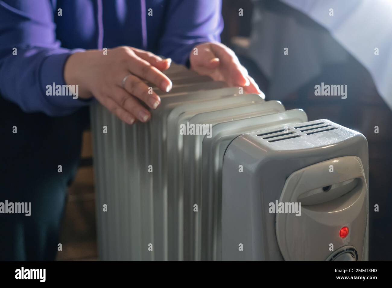 Female hands warming on oil heater at home close up. Cold winter with