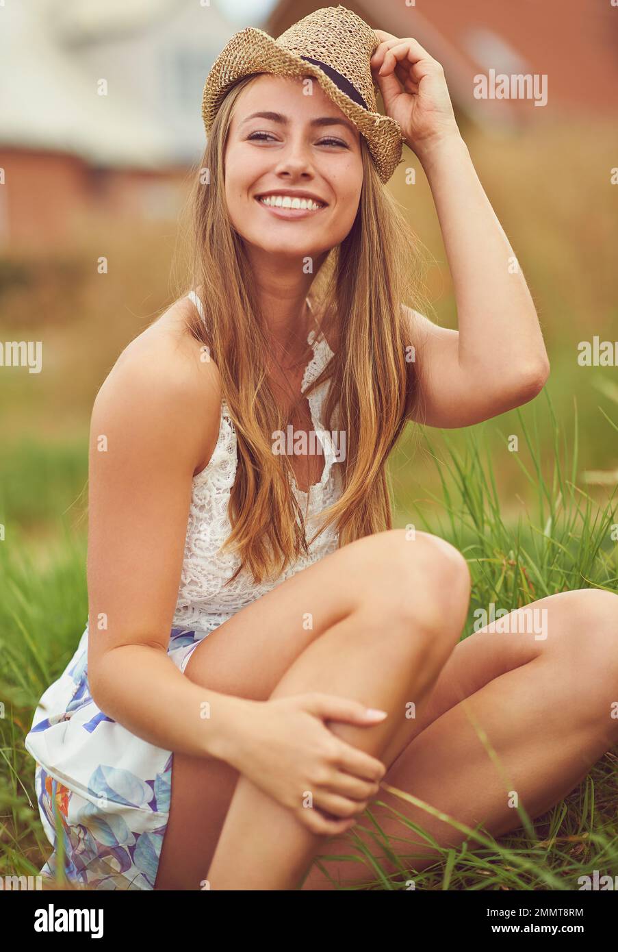 Find happiness in the simplest things. a young woman sitting in a field in the countryside. Stock Photo