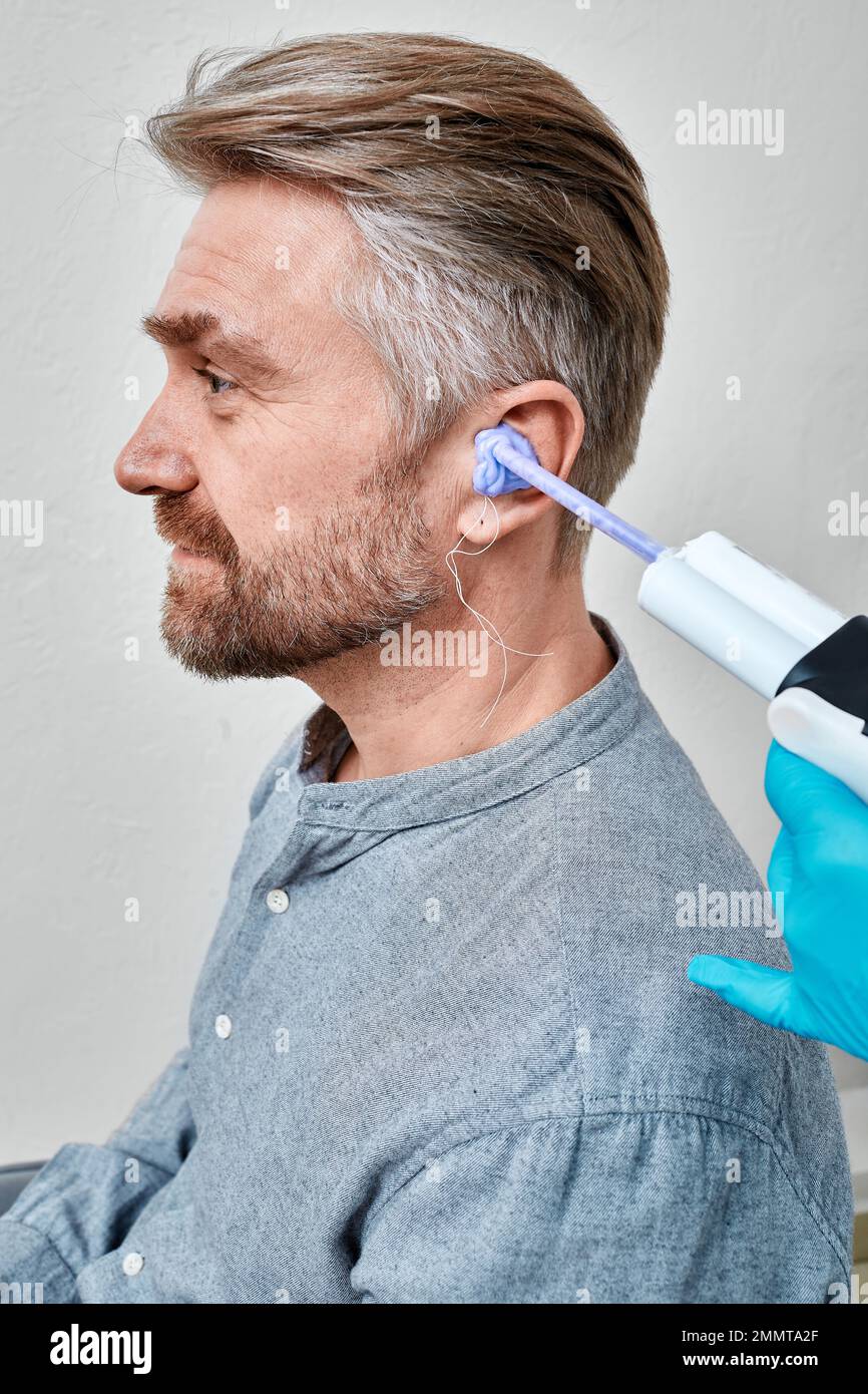 Doctor filling patient's ear canal with silicone material using syringe