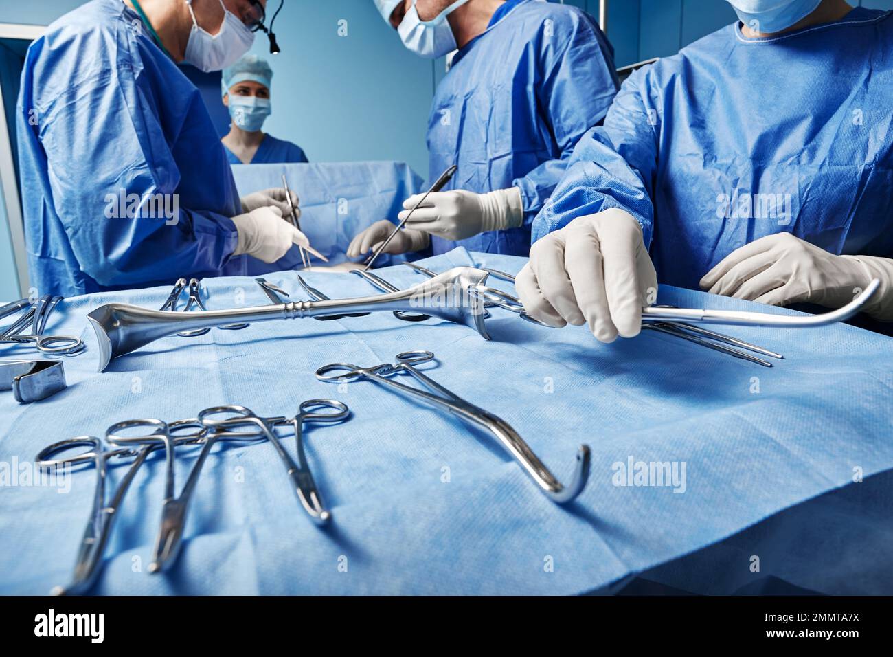 Surgical Team. Surgical nurse giving surgical scissors to male surgeon during operation in operating theatre Stock Photo