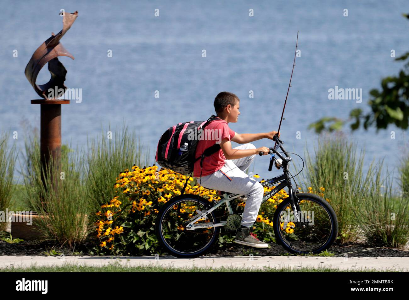 A boy holds a fishing pole while riding a bicycle along the banks of Lake Geneva, Friday, Aug. 10, 2018, in Geneva, N.Y. (AP Photo/Julio Cortez Stock Photo - Alamy A boy holds a fishing pole while riding a bicycle along the banks of Lake Geneva, Friday, Aug. 10, 2018, in Geneva, N.Y. (AP Photo/Julio Cortez Stock Photo - Alamy
