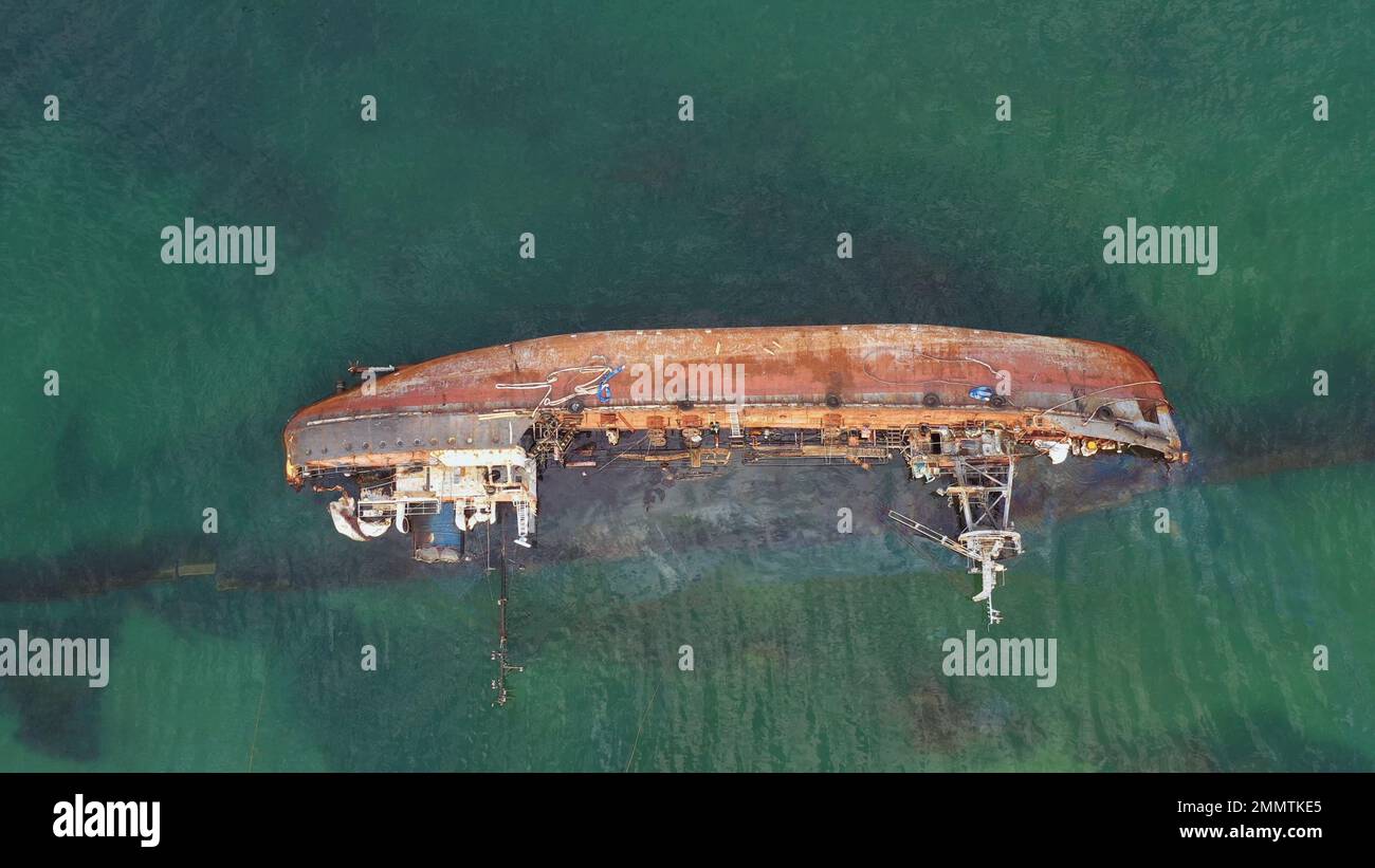 Overturned broken rusty oil tanker ship in the shallow water. Drowned ship after the wreck. Stock Photo