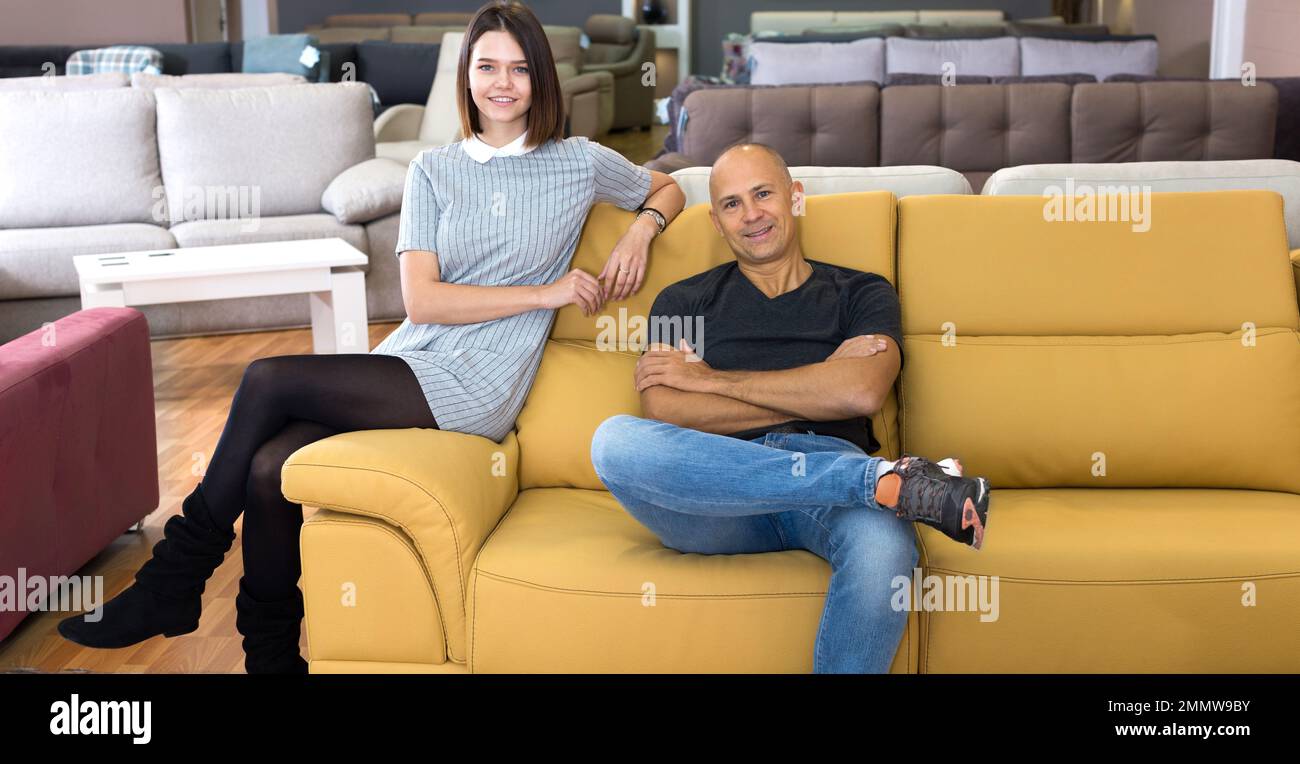 Couple sitting on yellow sofa Stock Photo