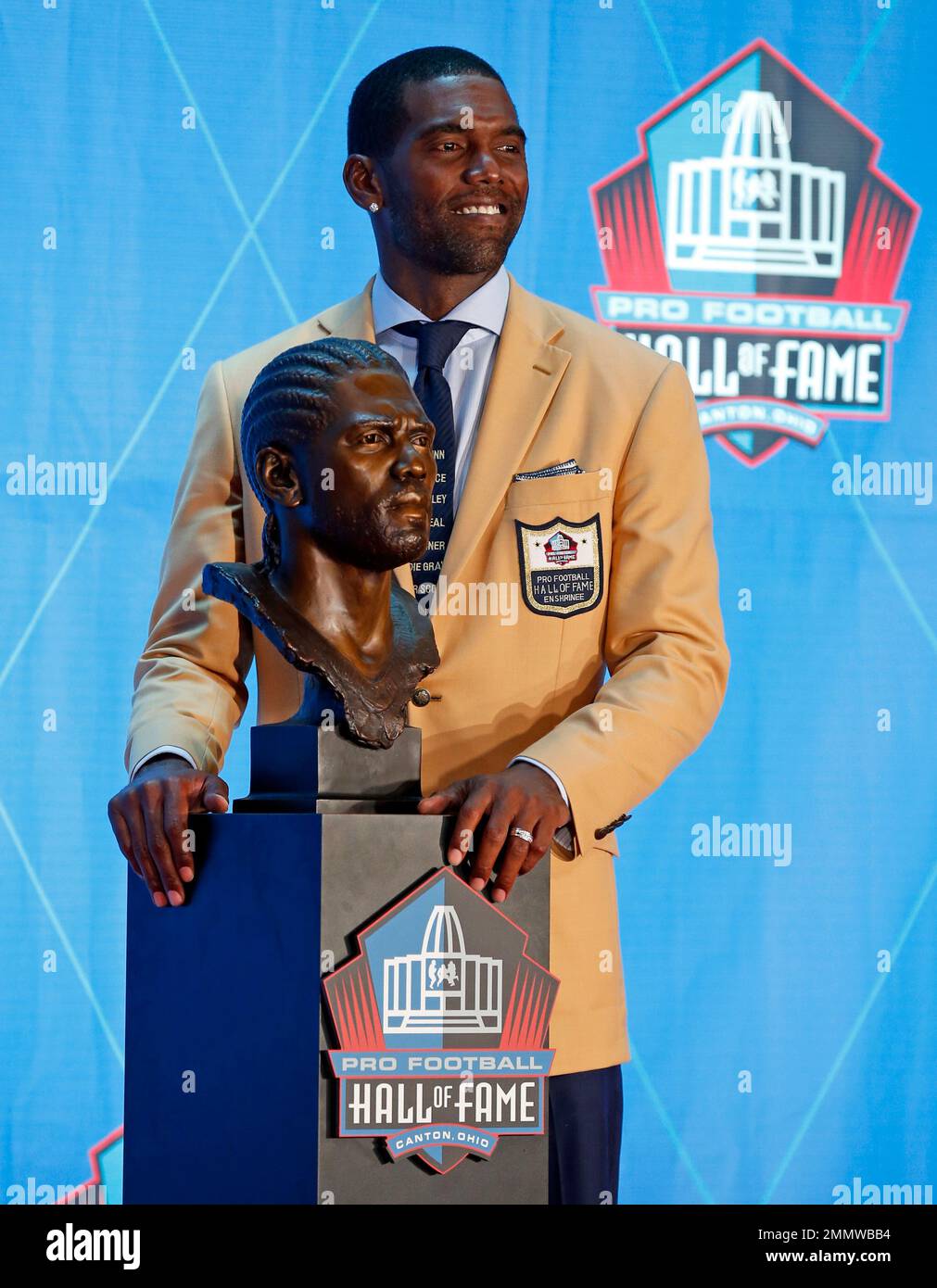 Former NFL player Randy Moss poses with a bust of himself during