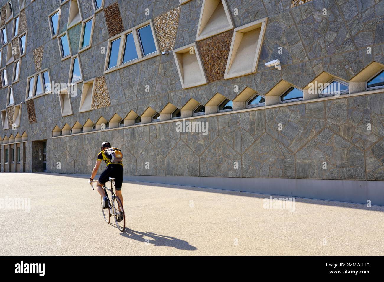 A cyclist rides on the sidewalk in front of the facade of the Grand Théâtre de la Ville de Luxembourg. Stock Photo
