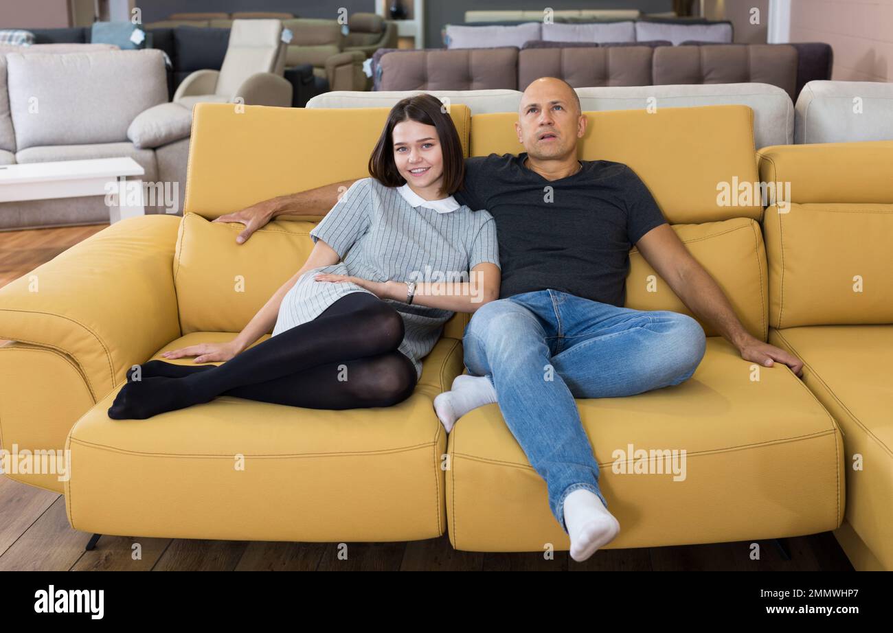 Couple sitting on yellow sofa Stock Photo