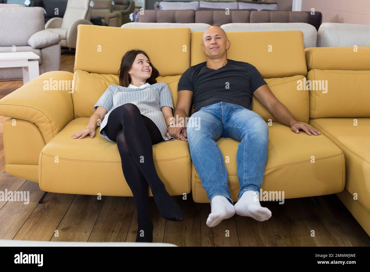 Couple sitting on yellow sofa Stock Photo