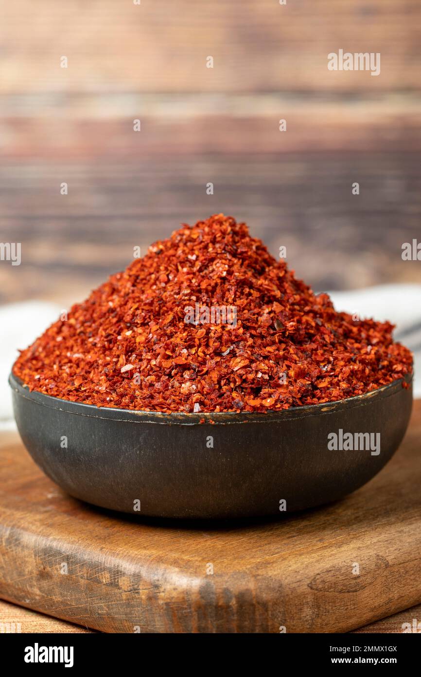 Red pepper flakes. Crushed chili pepper in bowl, dried chili flakes on wooden background. Close
