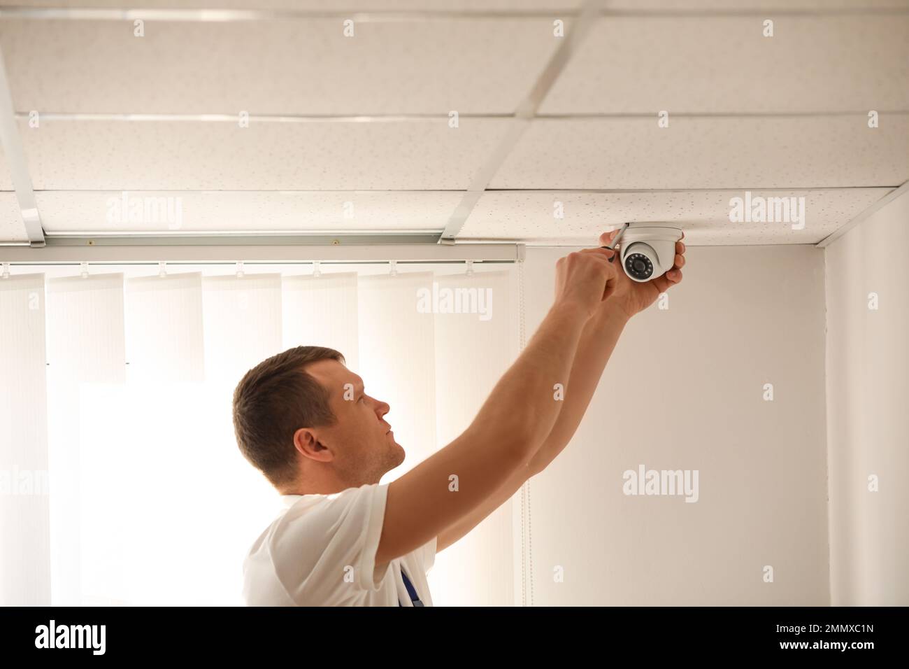 Technician installing CCTV camera on ceiling indoors Stock Photo - Alamy