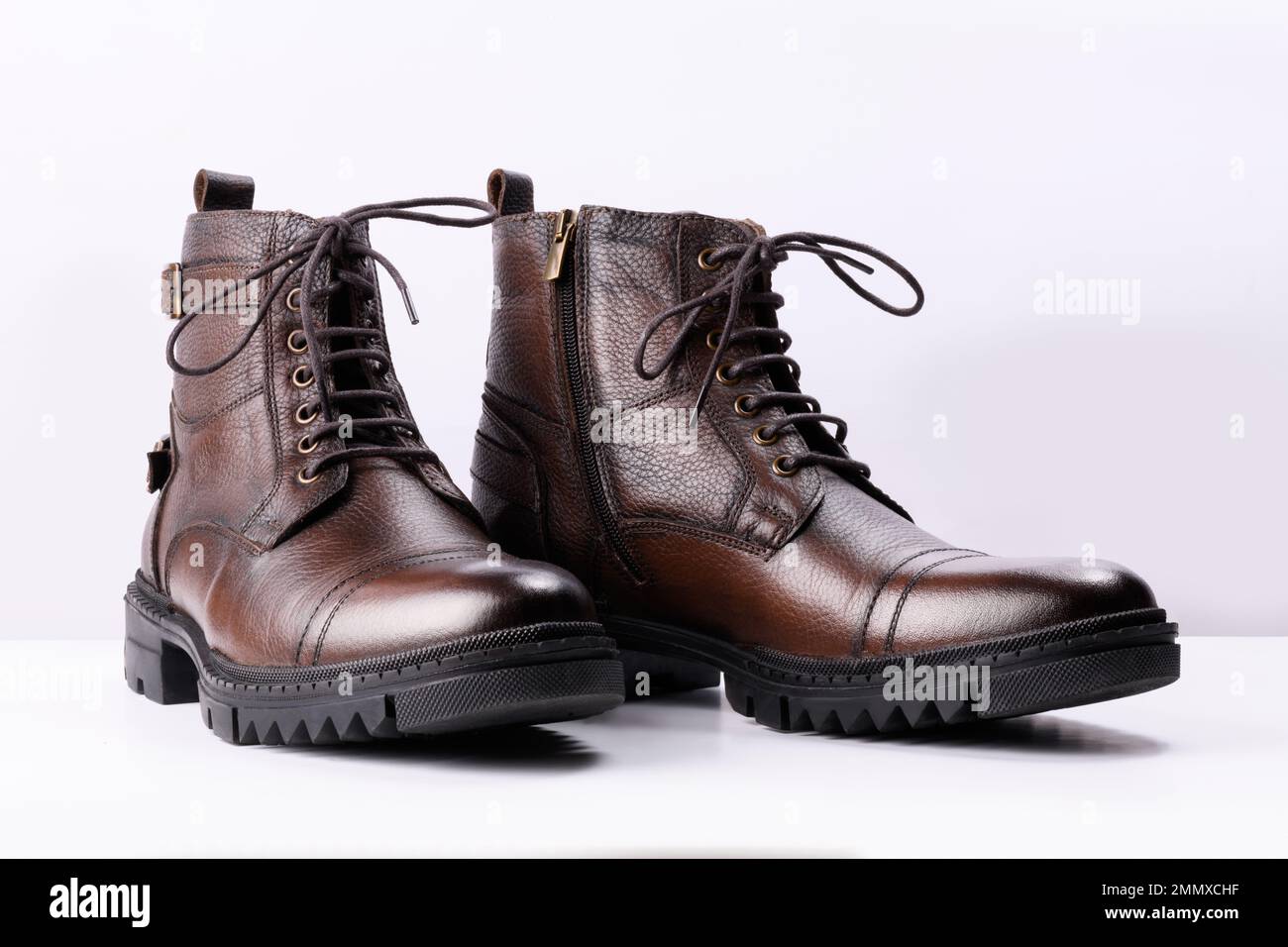 A pair of brown colored leather boots on a white background. Stock Photo