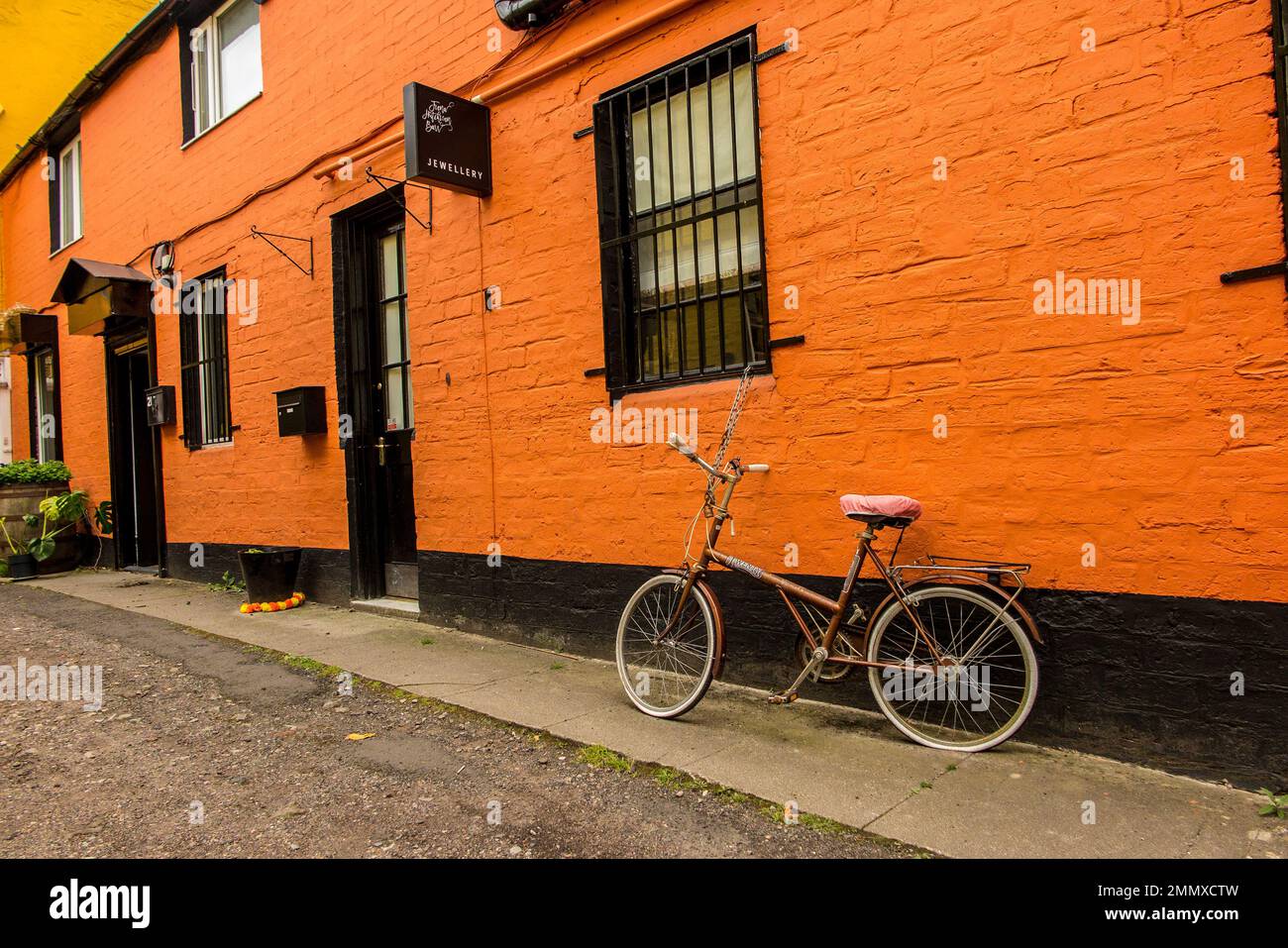 Bicycle parked outside jewellery boutique with orange painted wall in the Hidden Lane, Glasgow. Stock Photo