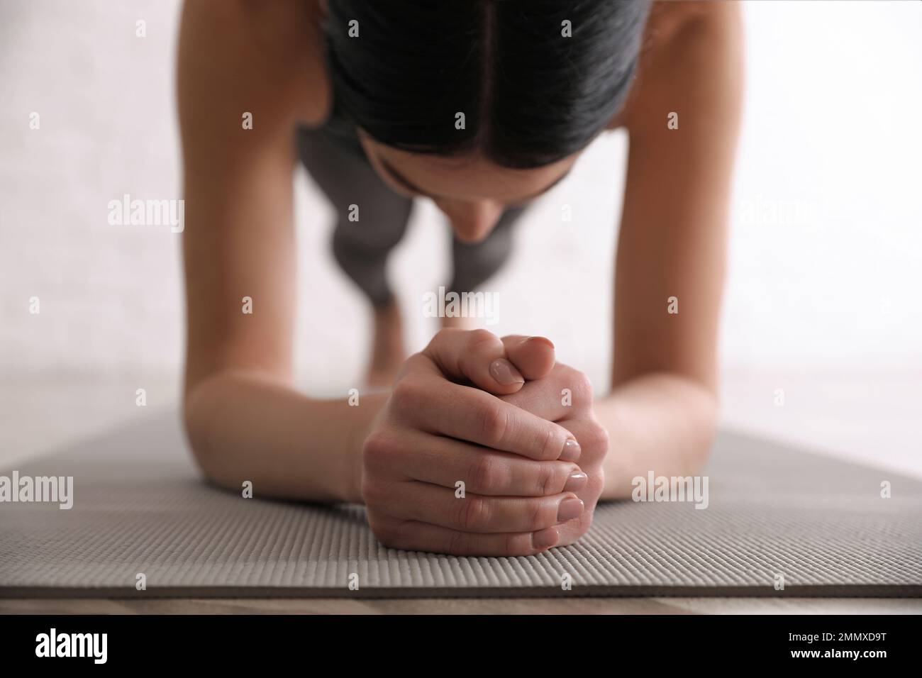 Young woman practicing forearm plank asana in yoga studio, closeup. Phalankasana pose variation Stock Photo
