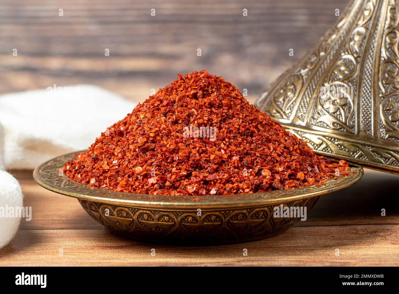 Red pepper flakes. Crushed chili pepper in bowl, dried chili flakes on wooden background. Close