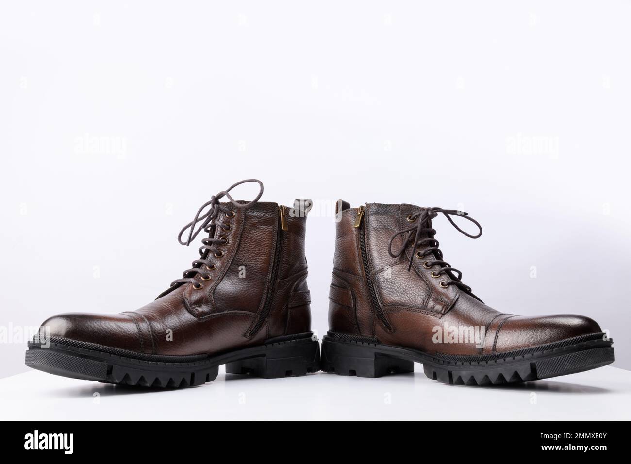 A pair of brown colored leather boots on a white background. Stock Photo