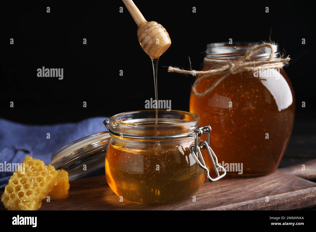 Honey dripping into jar on wooden board Stock Photo - Alamy