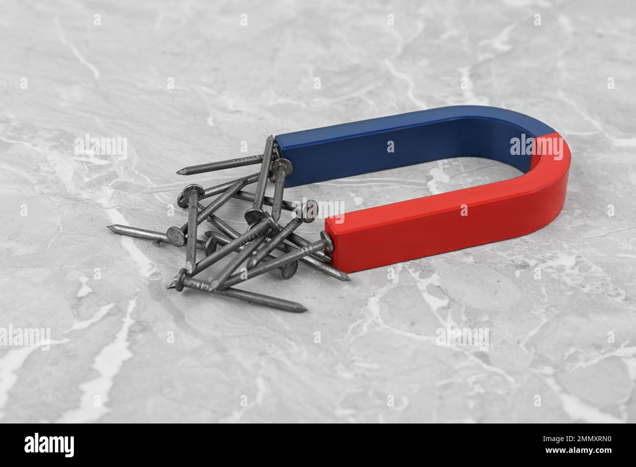 Horseshoe attracting nails on grey marble table Stock Photo Alamy