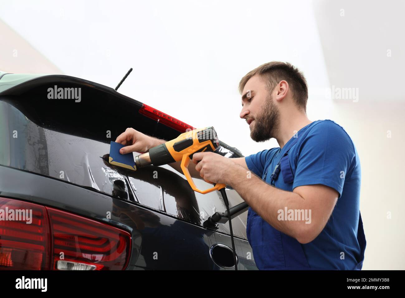 Worker tinting car window with heat gun in Stock Photo Alamy