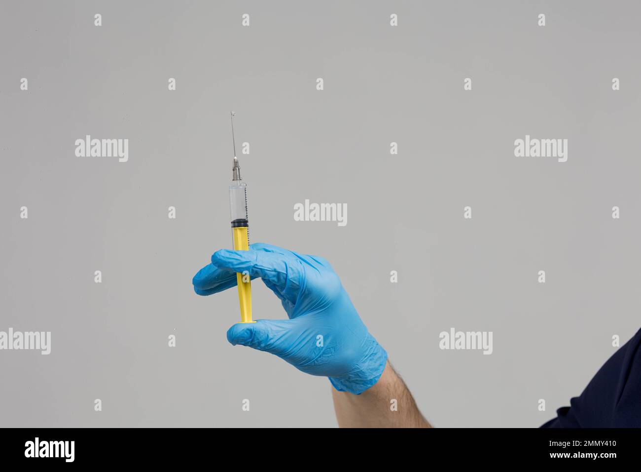 Closeup doctor's hand in rubber glove holding transparent syringe without cap with vaccine on light background. Concept of rejection of vaccinations Stock Photo