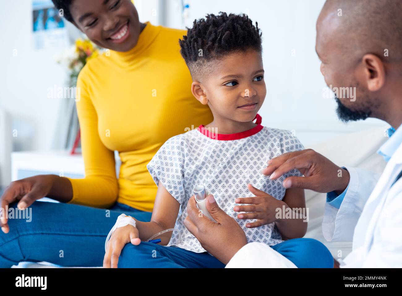 African american male doctor explaining inhaler to boy patient, with ...