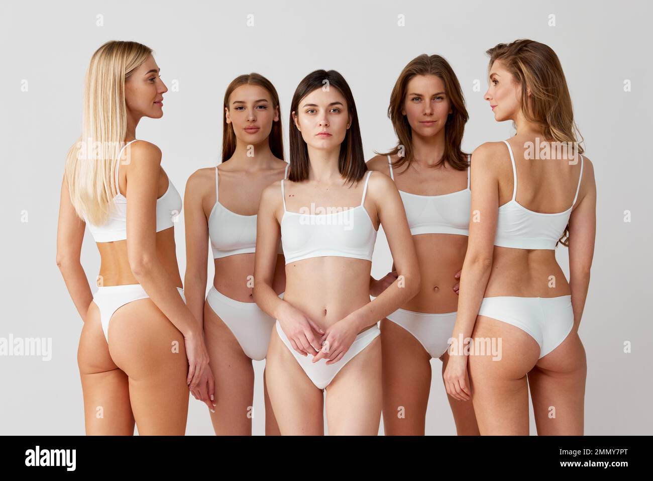 Group of diverse young women posing in white underwear over grey studio background. Femininity, body-positivity. Concept of natural beauty, body care Stock Photo