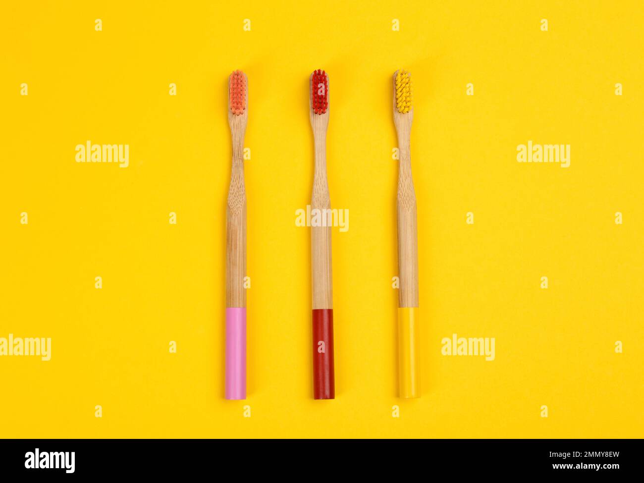 Toothbrushes made of bamboo on yellow background, flat lay. Space for ...