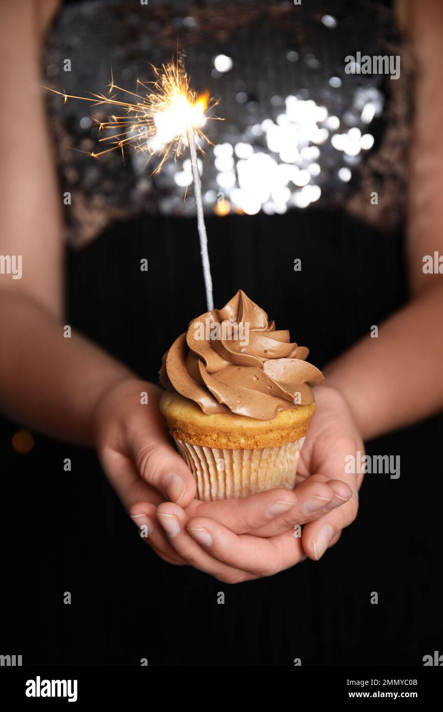 Woman holding birthday cupcake with sparkler, closeup Stock Photo