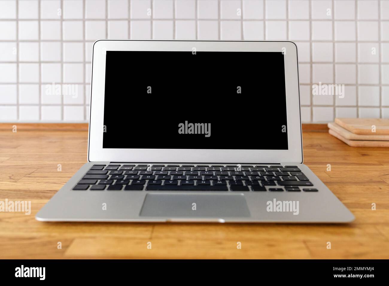 Laptop computer with blank mockup screen on kitchen counter, selective focus Stock Photo