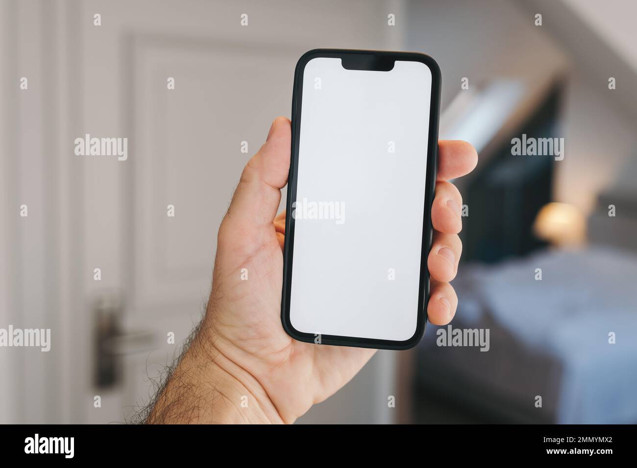 Tourist in hotel bedroom holding smartphone with blank mockup screen for booking and reservation app or accommodation rating service Stock Photo