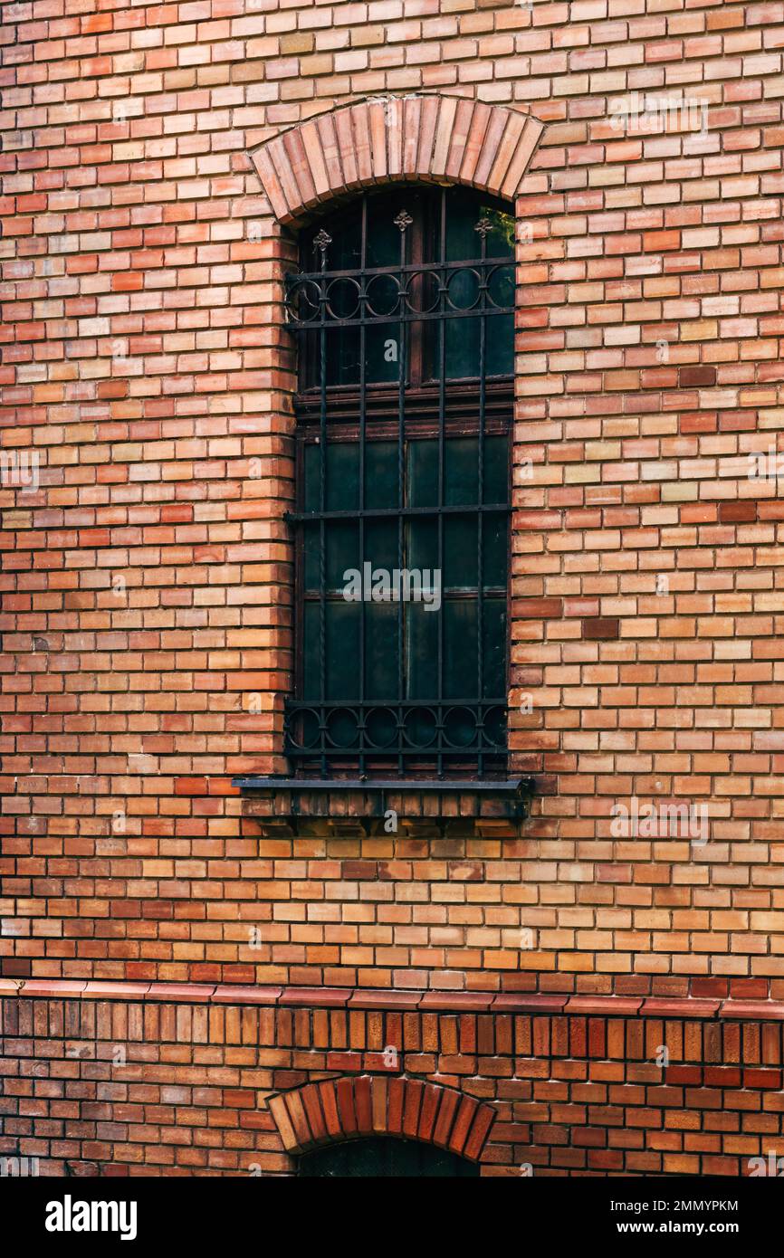 Old vintage brick wall and window with protective metal bars on a building Stock Photo