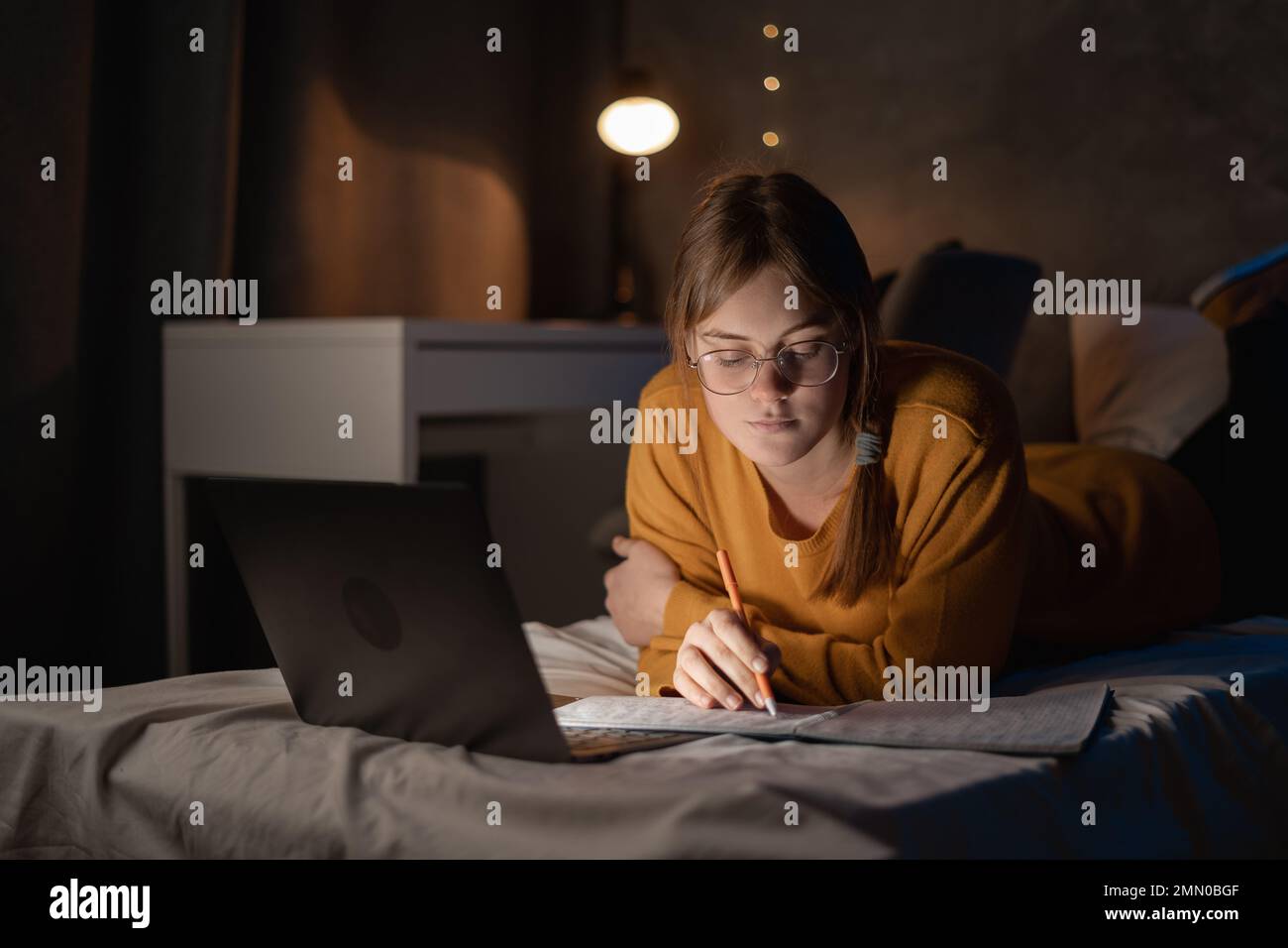 Girl student studying at night in dormitory using laptop computer on