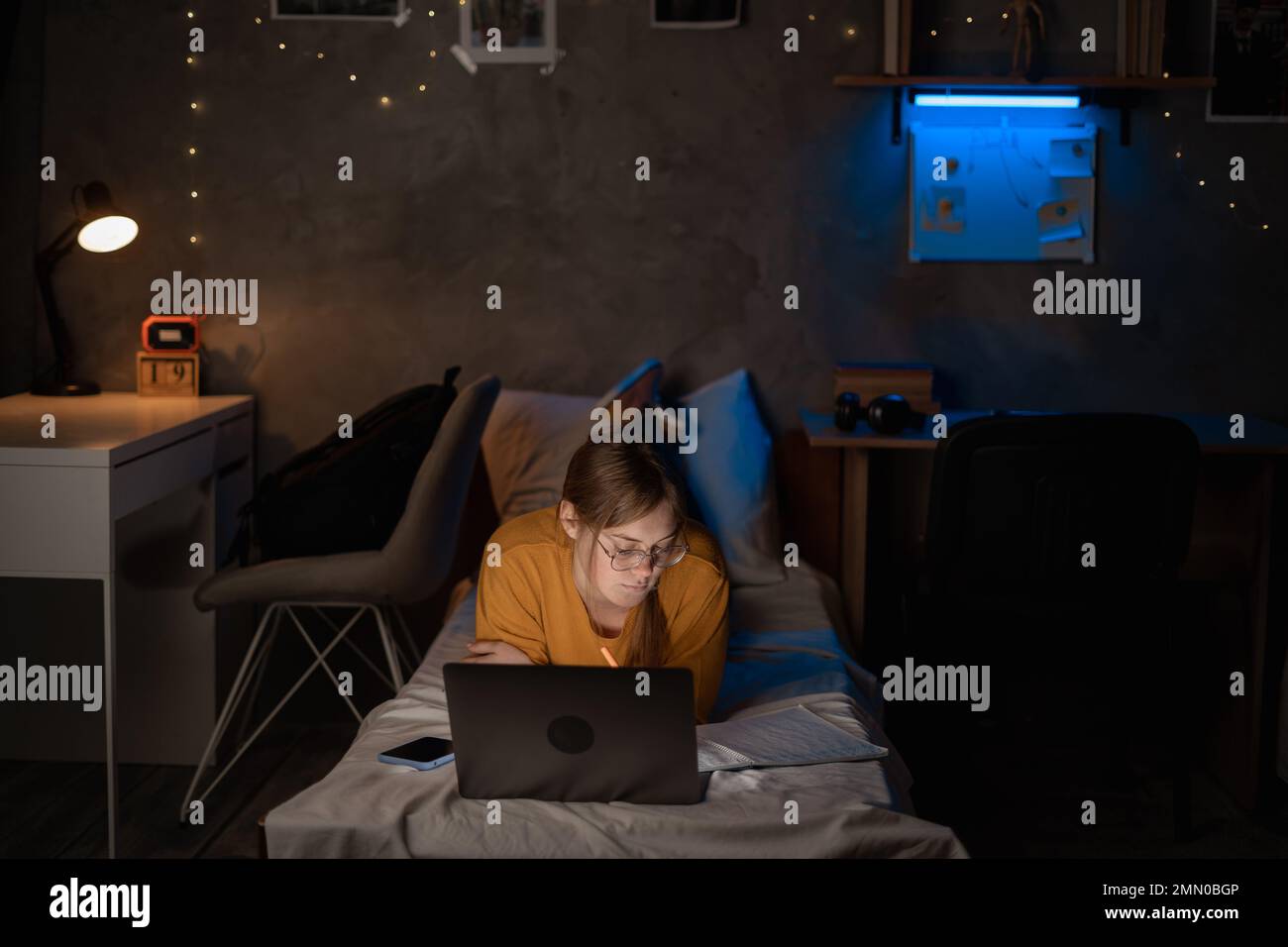 Girl student studying at night in dormitory using laptop computer on