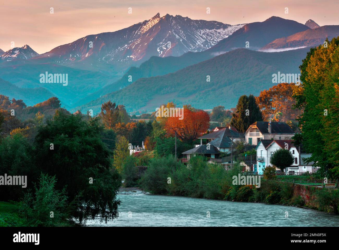 France, Pyrenees Atlantiques, Bearn, Nay, sunrise over a mountainous landscape where a river flows, lined with houses in autumn Stock Photo