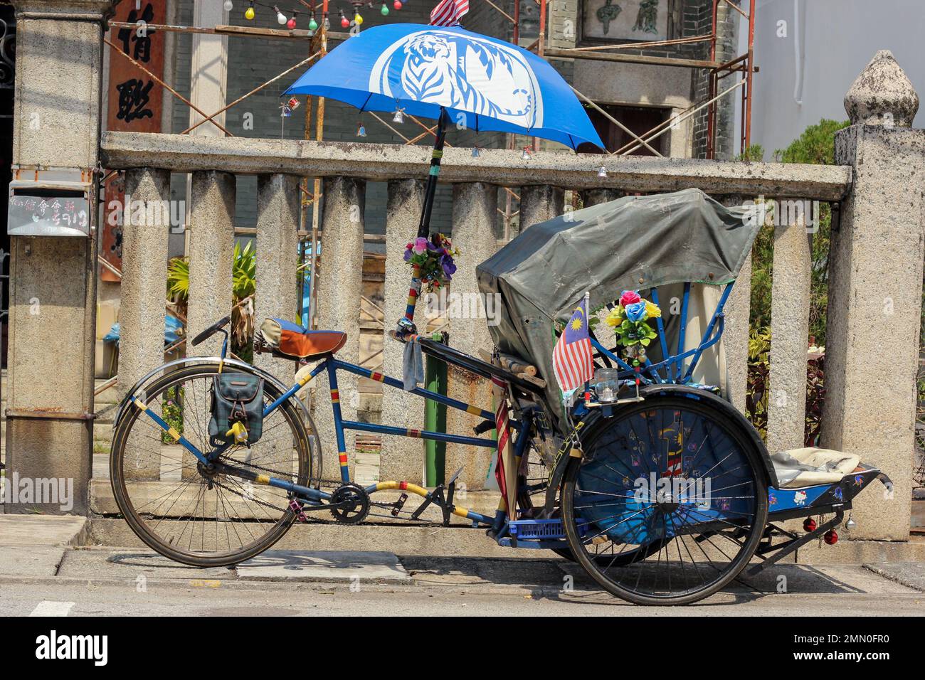 Penang, Malaysia November 2012 A cycle rickshaw with a blue umbrella parked on a