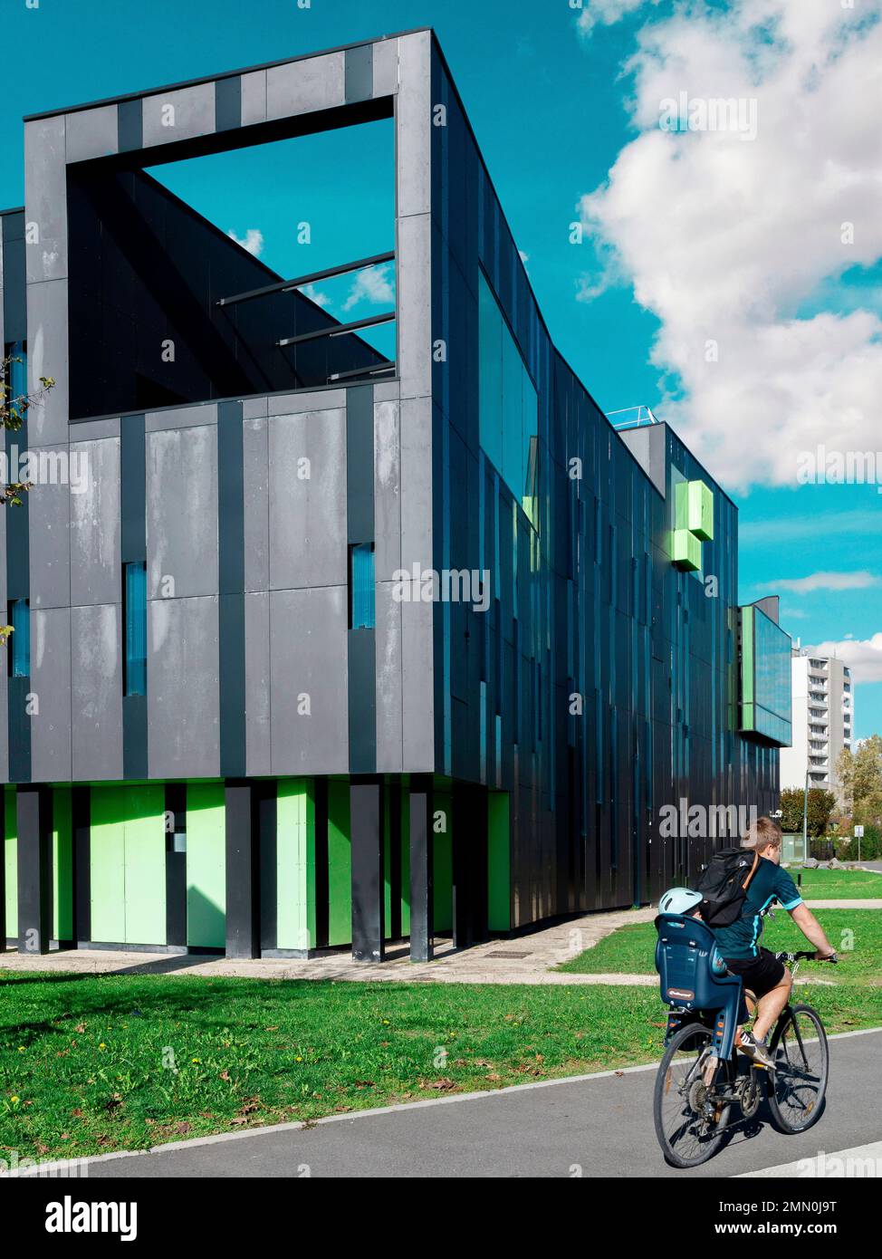 France, Pyrenees Atlantiques, Bearn, Pau, father carrying a child on his bicycle on a proper track passing in front of a contemporary building Stock Photo