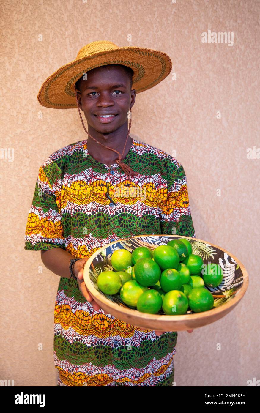 Senegal, Saloum delta listed as World Heritage by UNESCO, Palmarin, Yokan lodge, young waiter in colorful wax outfit and straw hat carrying a tray full of limes Stock Photo